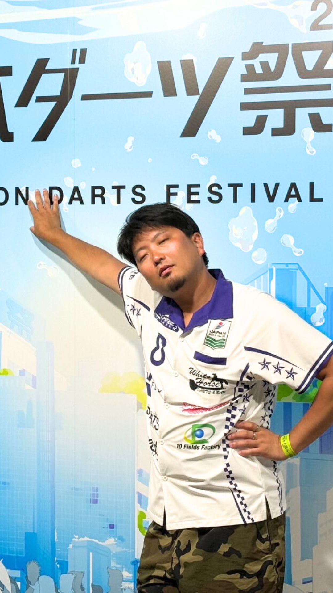 イベント出演時の風間佑太。バックパネルの前でポーズを決めるユニフォーム姿。カモフラ柄のショートパンツが目を引く。