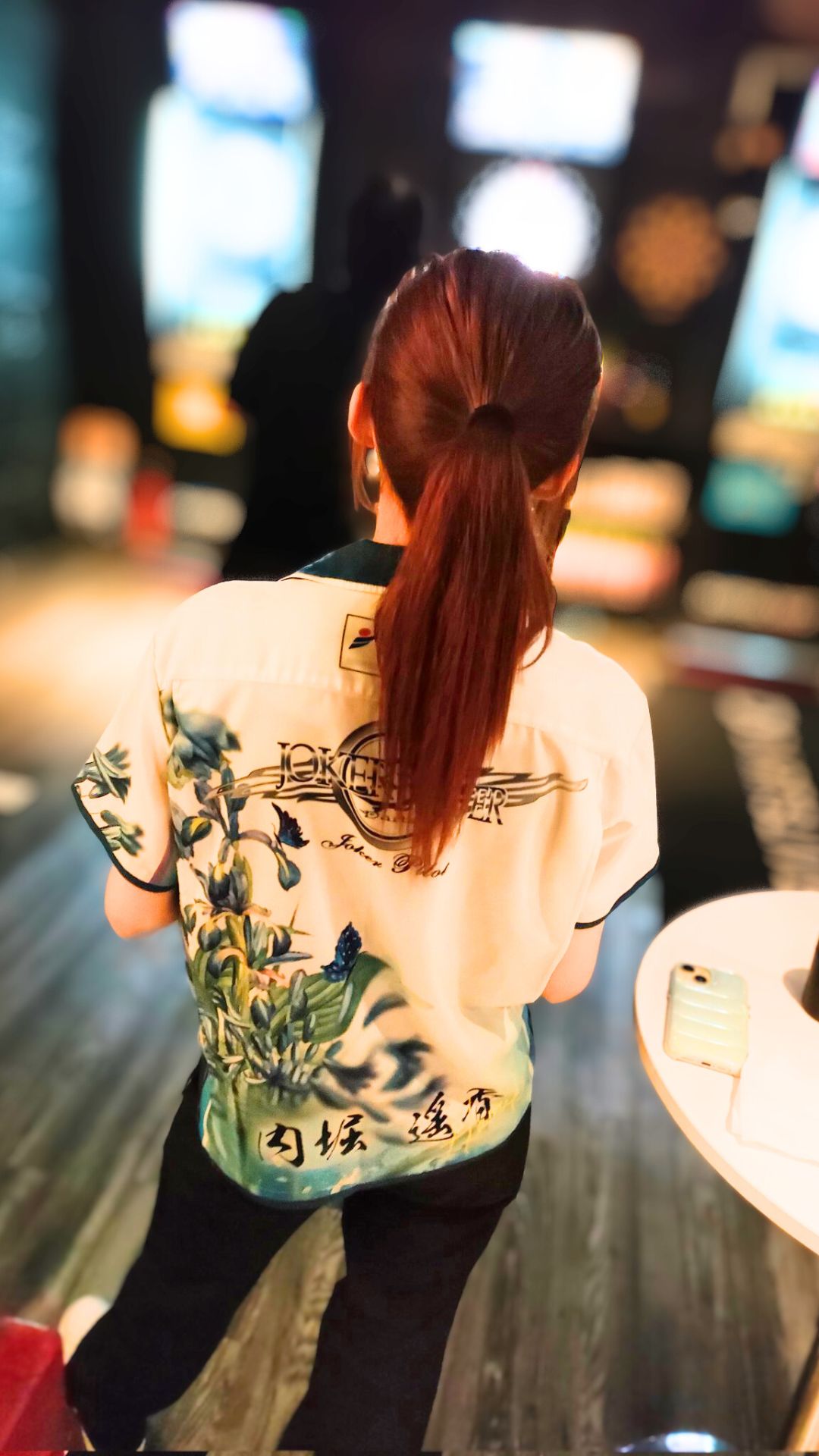 ダーツバーの店内で、ダーツ台に向かうプロダーツプレイヤー内堀遥香さんの後ろ姿