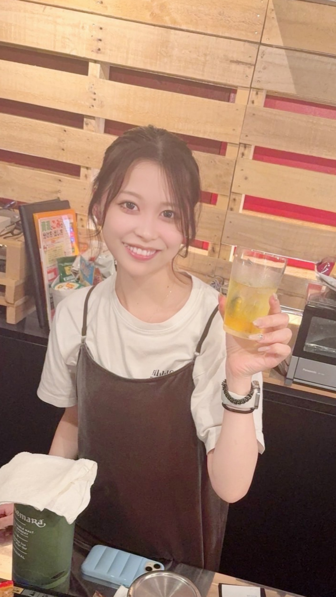 店舗カウンターでユニフォーム姿の女性プロダーツプレイヤー内堀遥香さん