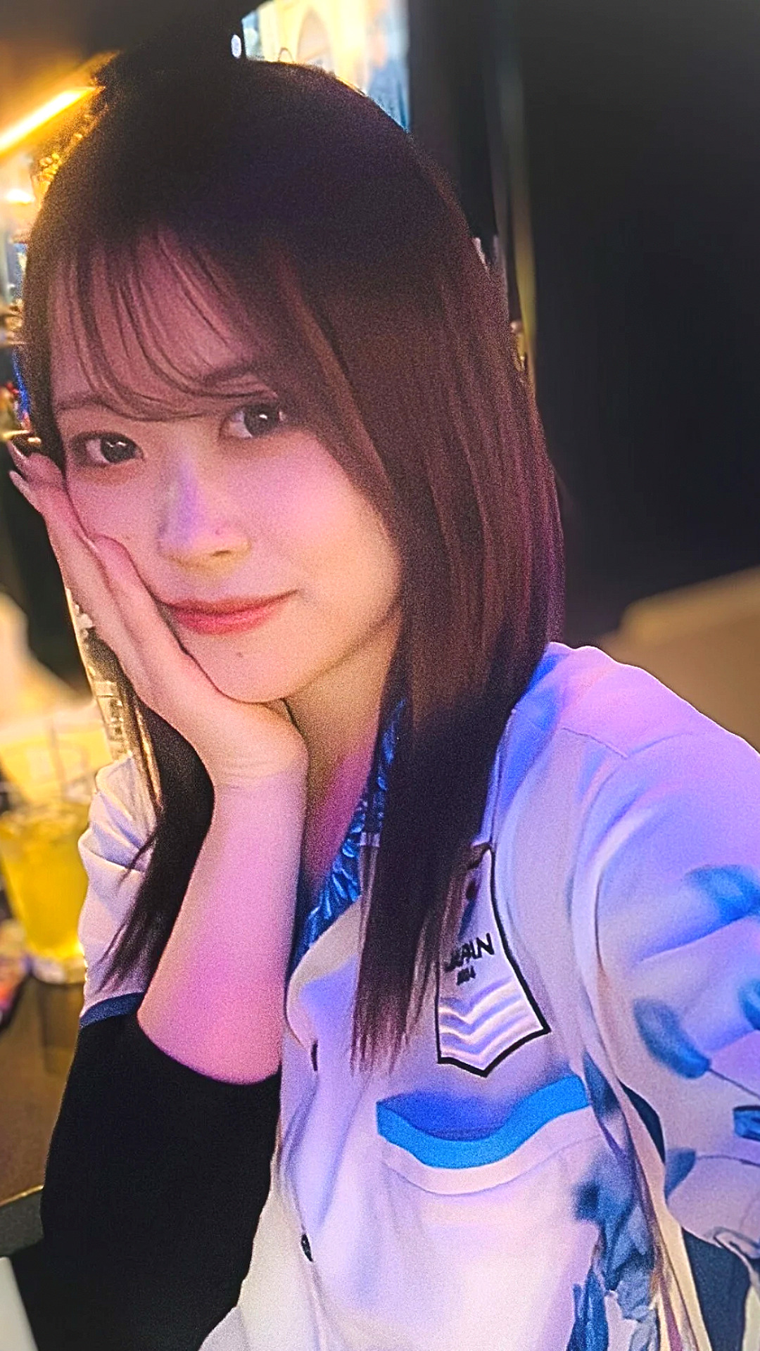 ポスター前でダーツを持ってポーズする女性ダーツプレイヤー内堀遥香さん