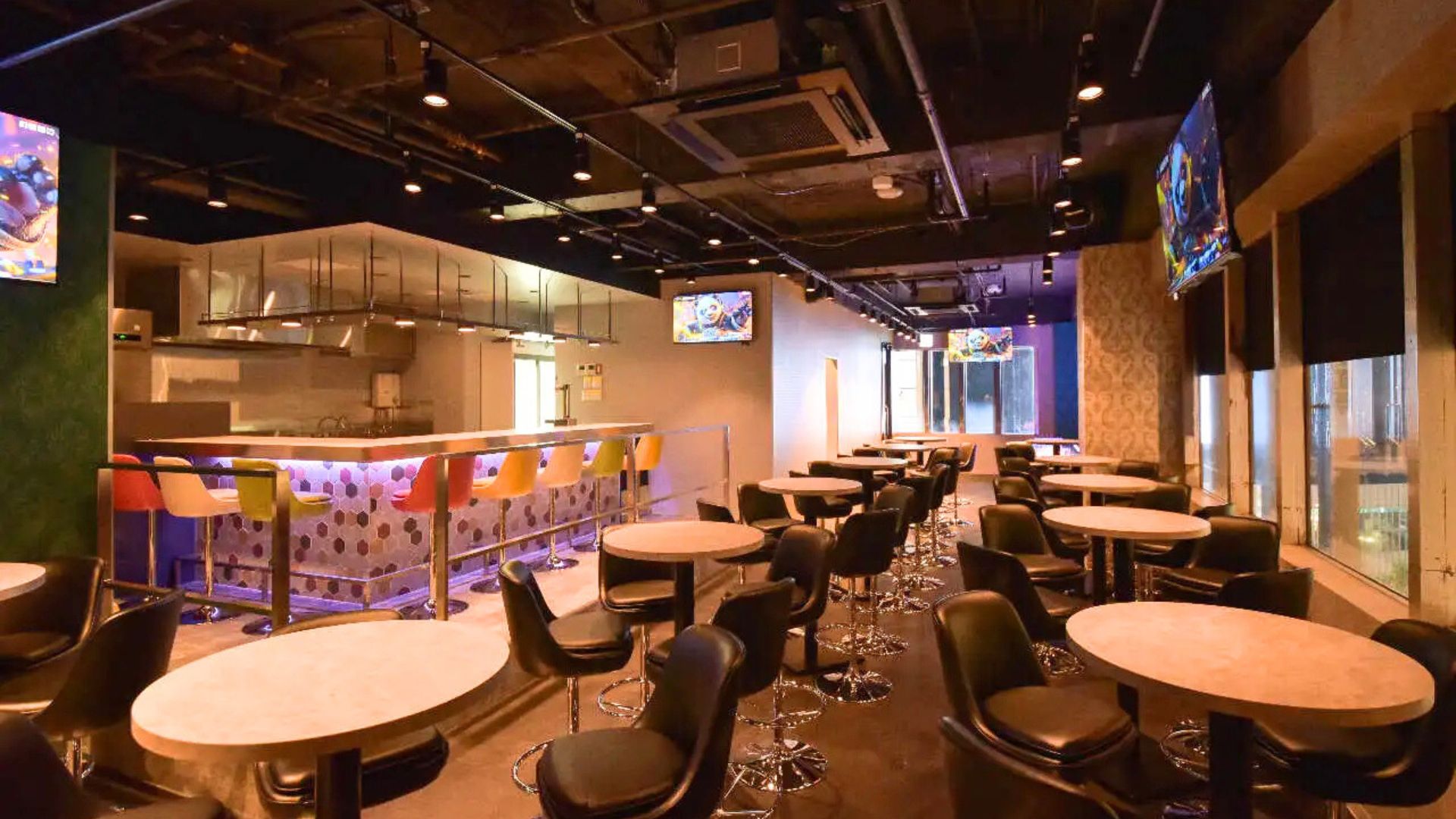 ライトアップされたダーツ&ビアポン BASE2 新宿歌舞伎町店のバーカウンター。様々なお酒のボトルが並び、おしゃれな雰囲気を演出している。