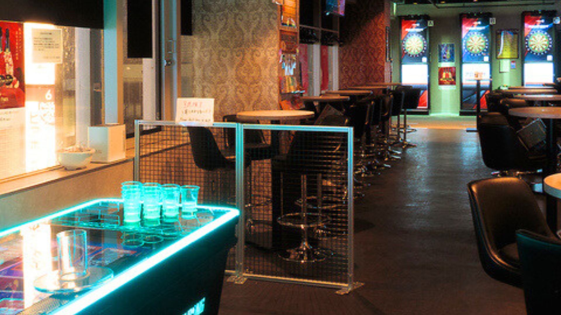 ダーツ&ビアポン BASE2 新宿歌舞伎町店に並ぶ4台のダーツマシン。画面が明るく点灯し、いつでもプレイできる状態。