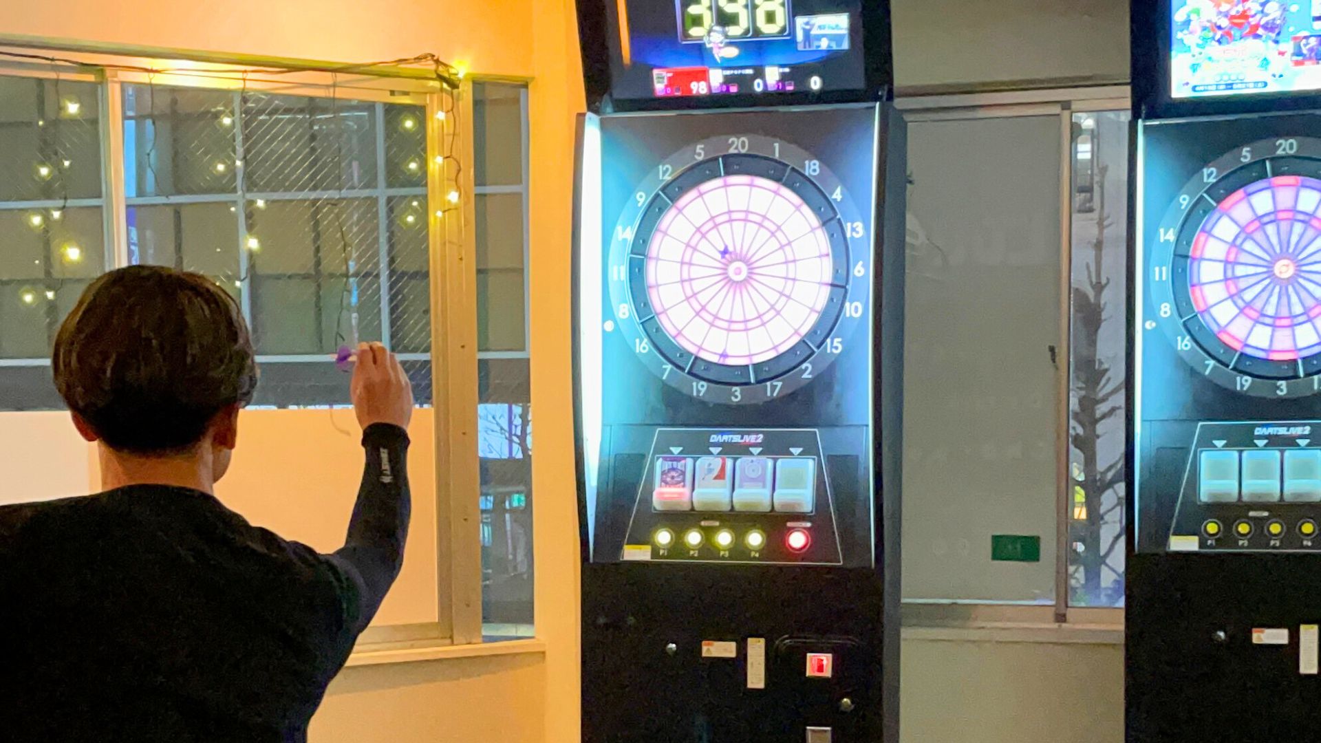 ダーツをプレイする男性。真剣な表情でボードを狙う